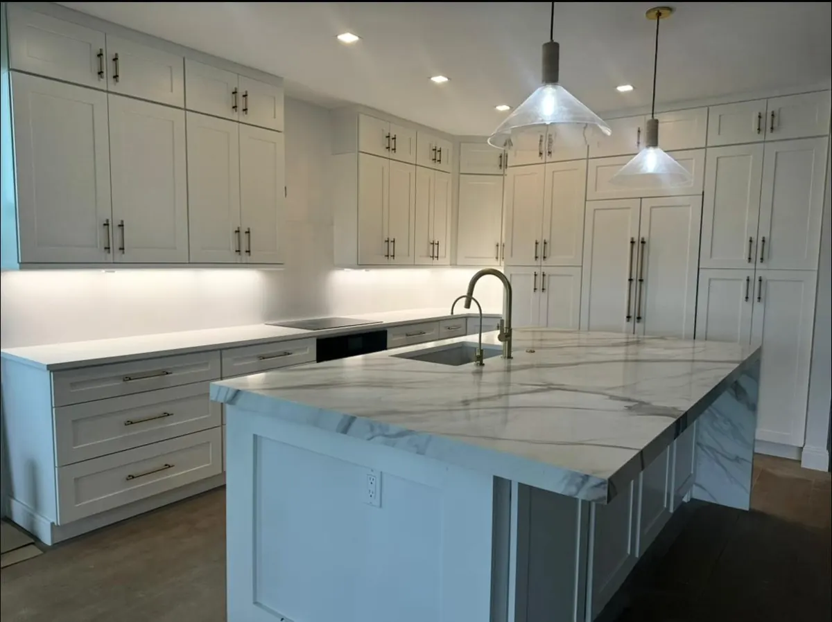 Large white kitchen with a marble-look island under pendant lights